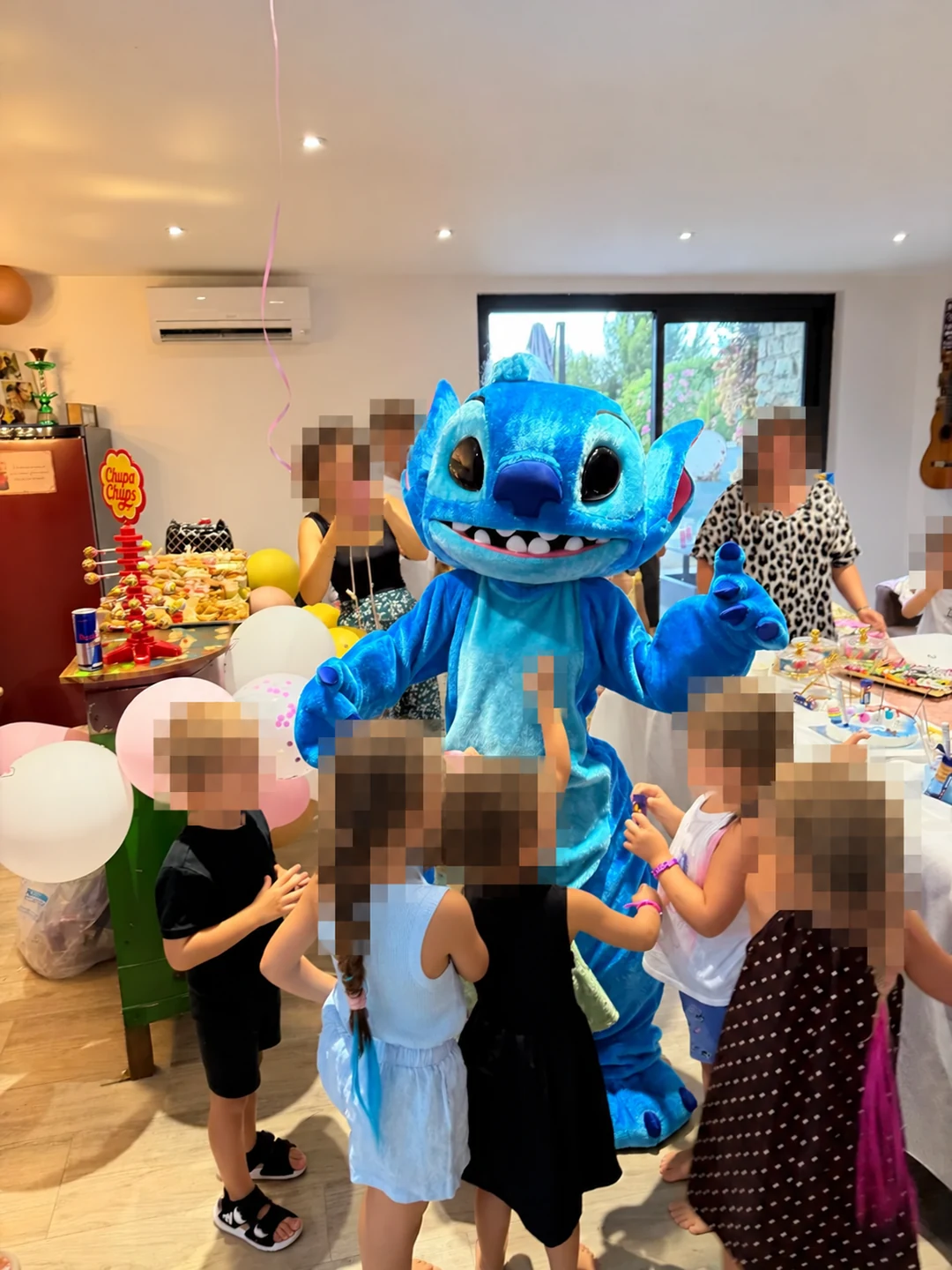 Mascotte Stitch lors d’une fête, visages des invités anonymisés