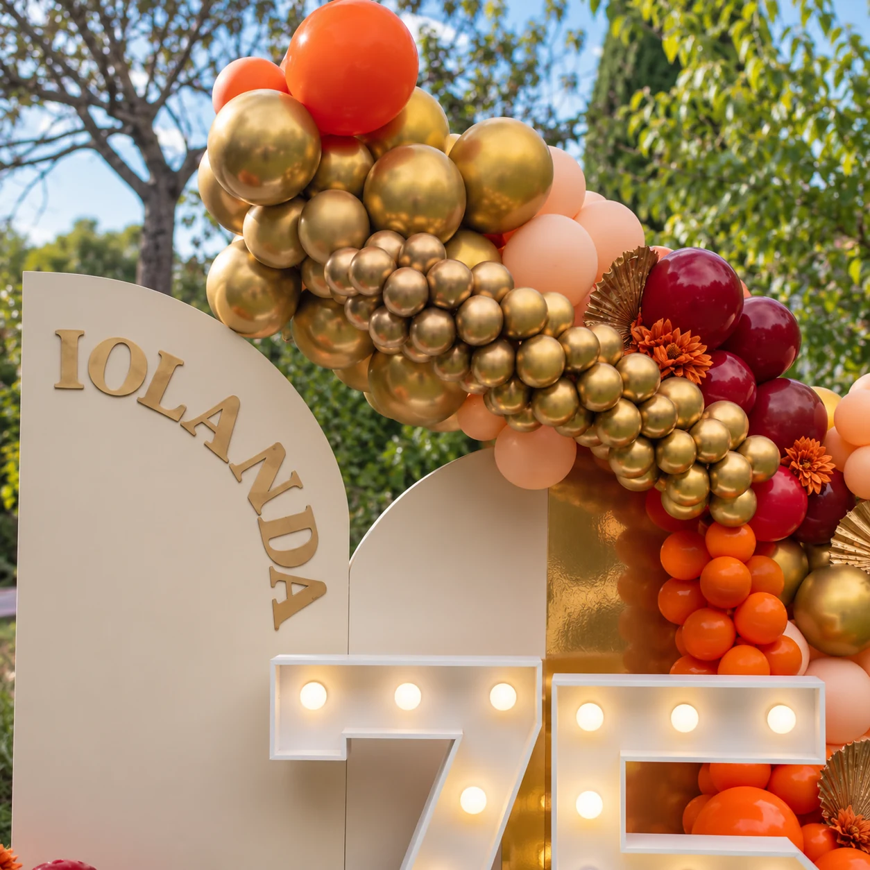 Détail du prénom Iolanda sur le panneau crème sous une arche de ballons dorés et de couleurs automnales