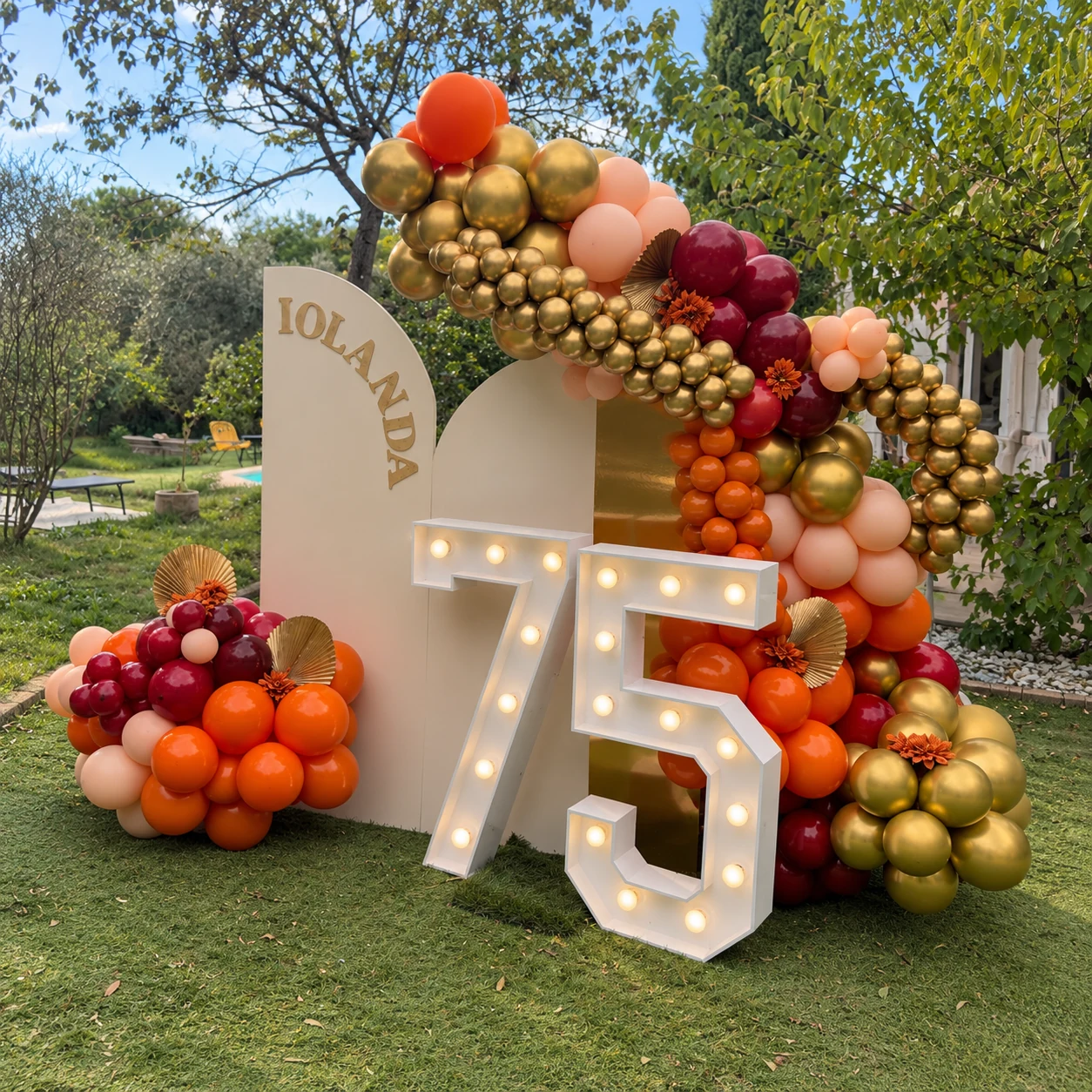 Vue de trois-quarts du décor Iolanda, ballons bordeaux orange et dorés et chiffres lumineux 75