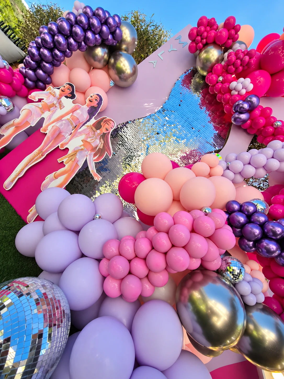 Ballons roses, lilas et violets métallisés, boules miroir et fond scintillant du décor de Myla