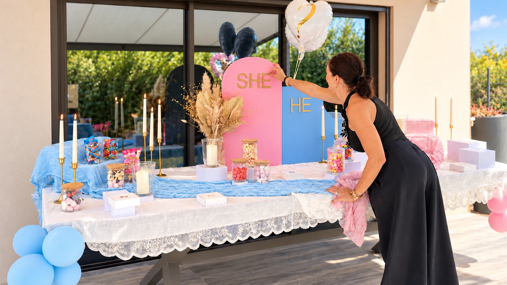 Buffet de la gender reveal avec panneaux SHE et HE, bougies et décoration pastel