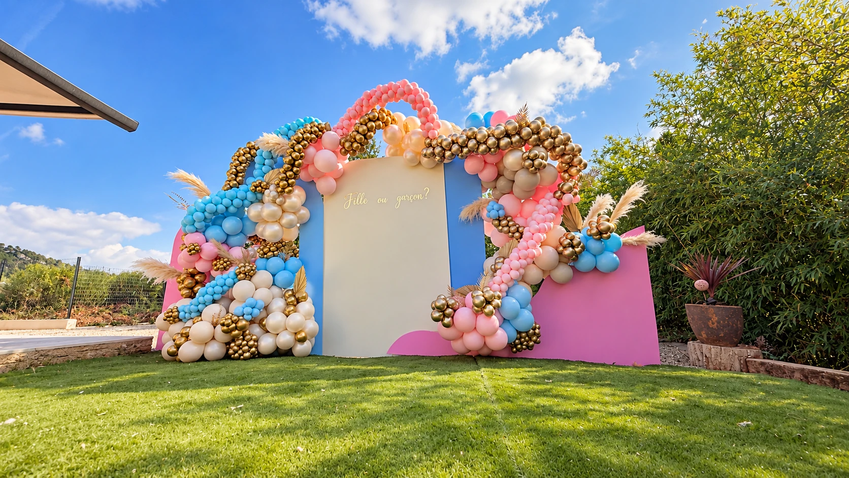 Vue large du décor de gender reveal au jardin, avec panneaux et ballons pastel