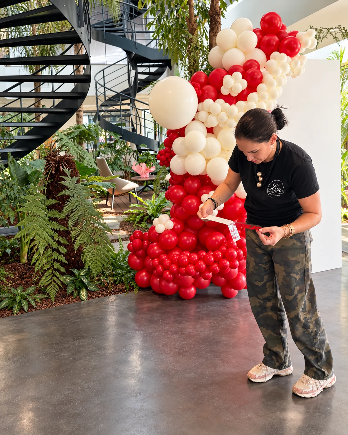 Charlène prépare la personnalisation du décor Flavine au pied de la composition de ballons rouges