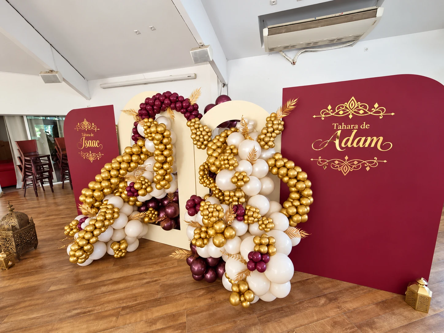 Vue latérale du décor de Tahara avec panneaux bordeaux et compositions de ballons ivoire et or